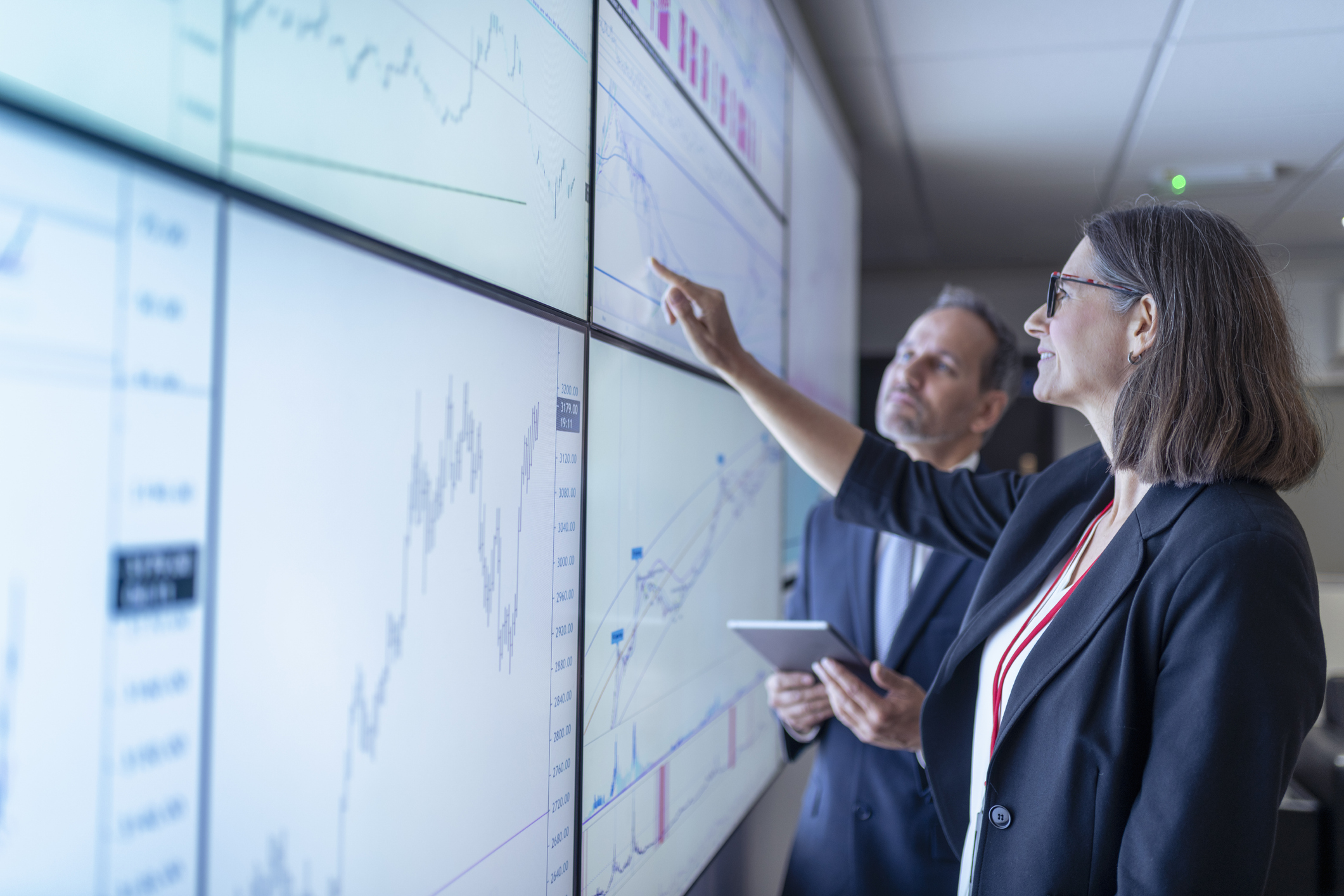 2 people looking at graphs in a big screen