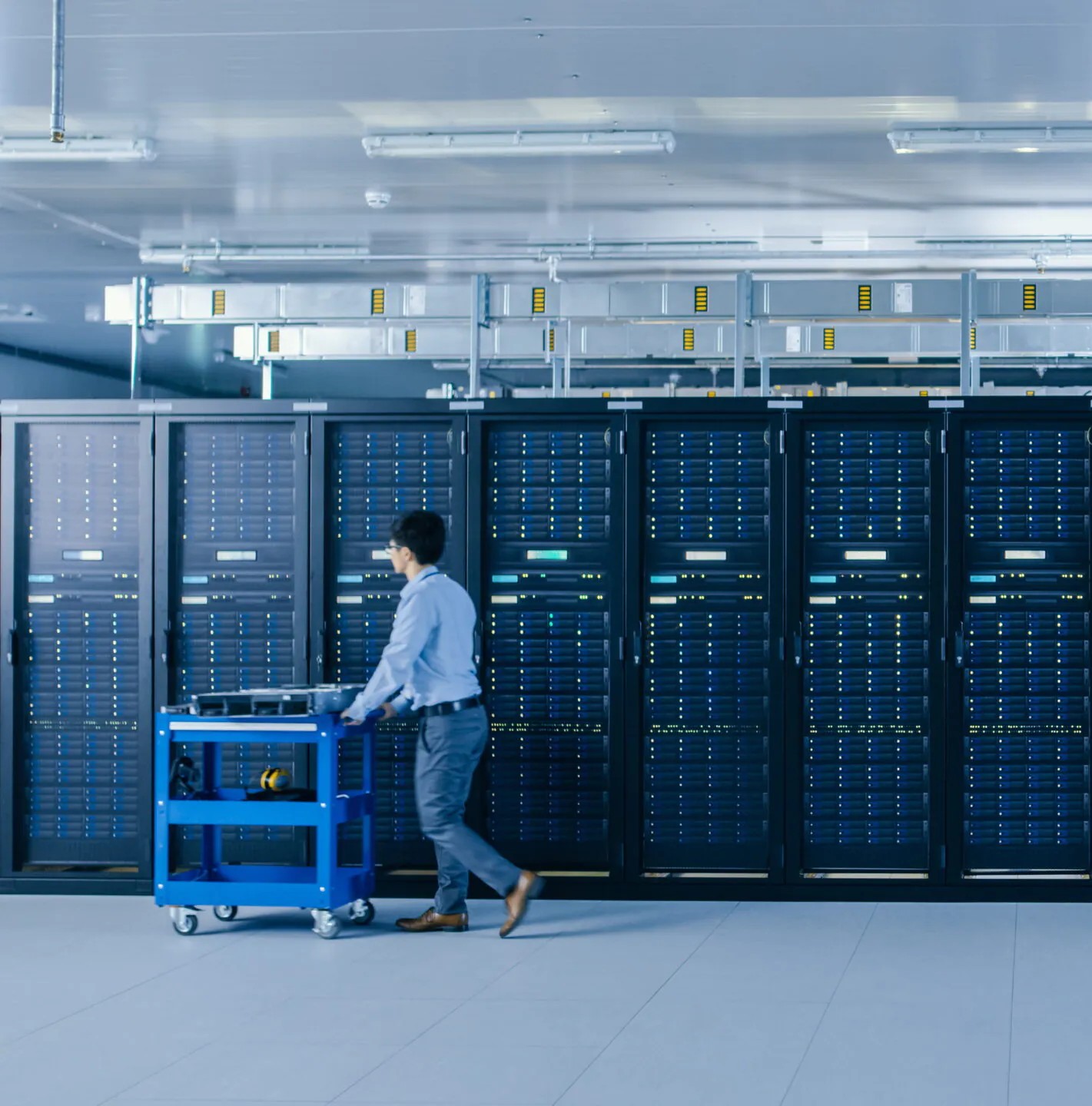 A man pushing a cart with equipment in a data center