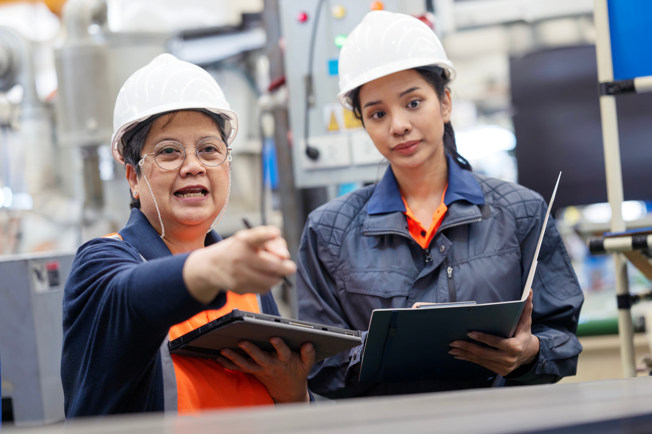 A Senior female Asian manager with a Maintenance Engineer having a meeting in front of the machinery