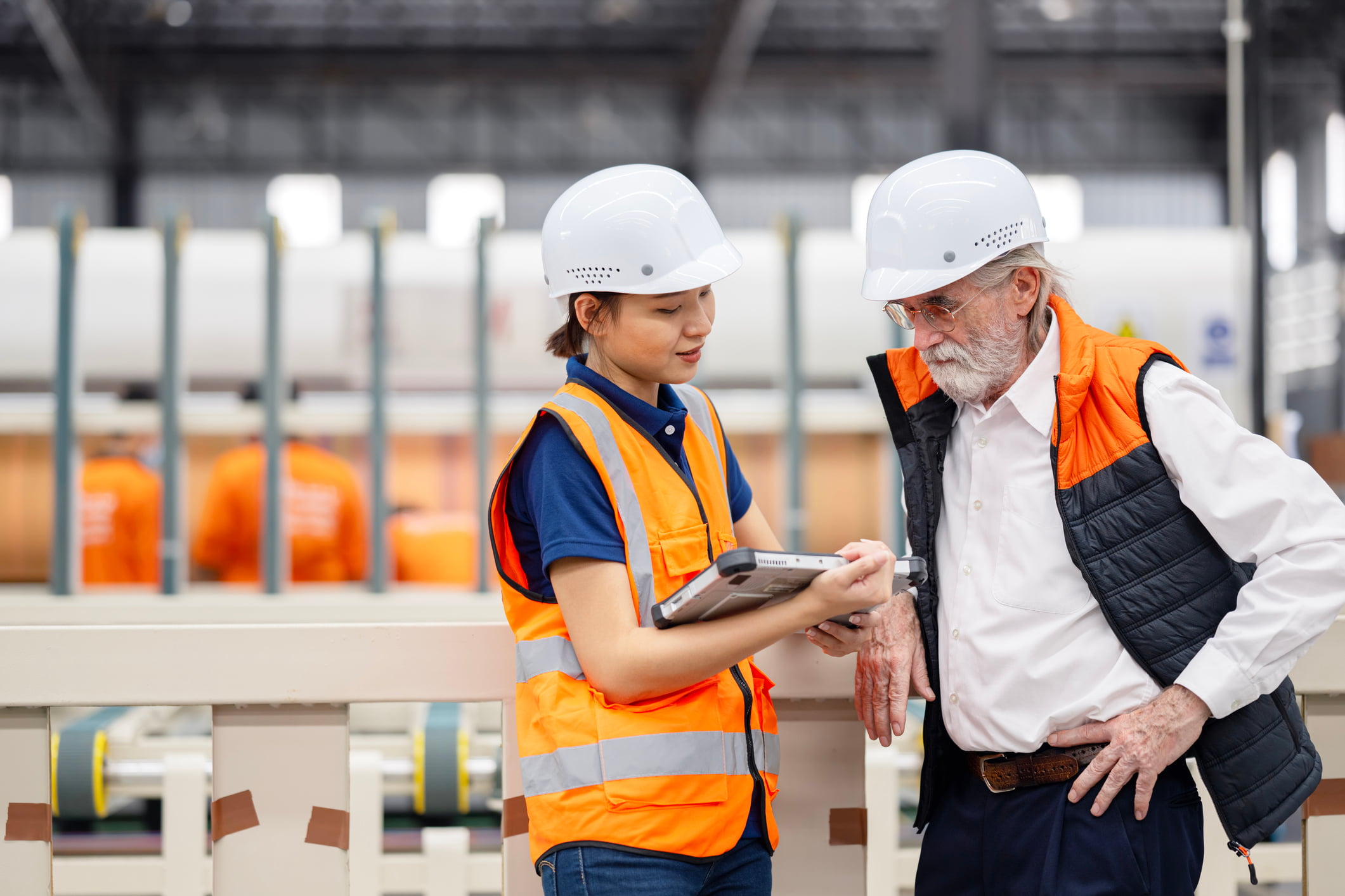 A female production supervisor reports production data over a tablet computer to a business owner in a production line.
