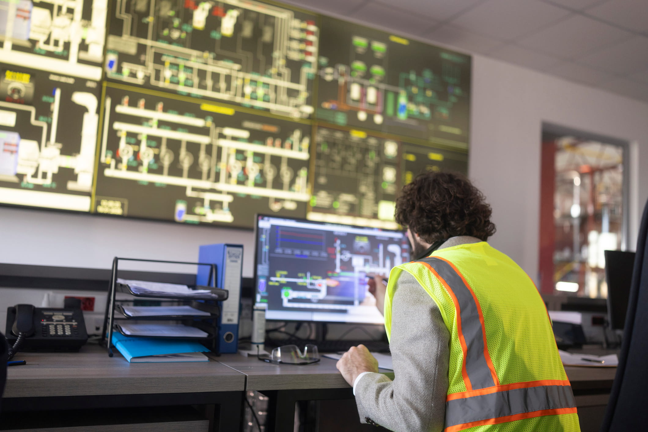 An industrial operator in a safety vest monitors complex energy generation systems through advanced digital interfaces