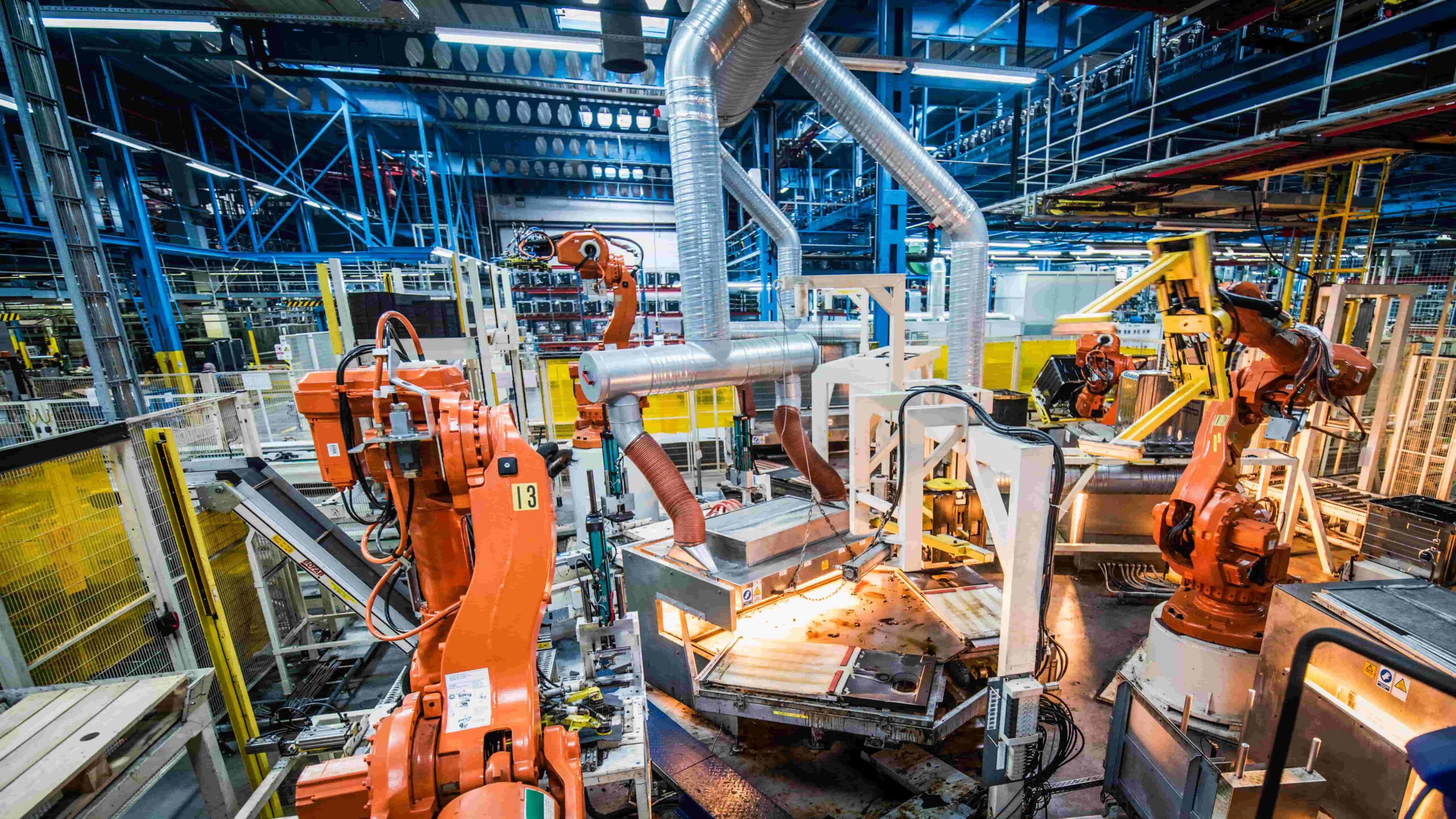 Industrial manufacturing facility with multiple robotic arms performing automated production tasks on an advanced assembly line