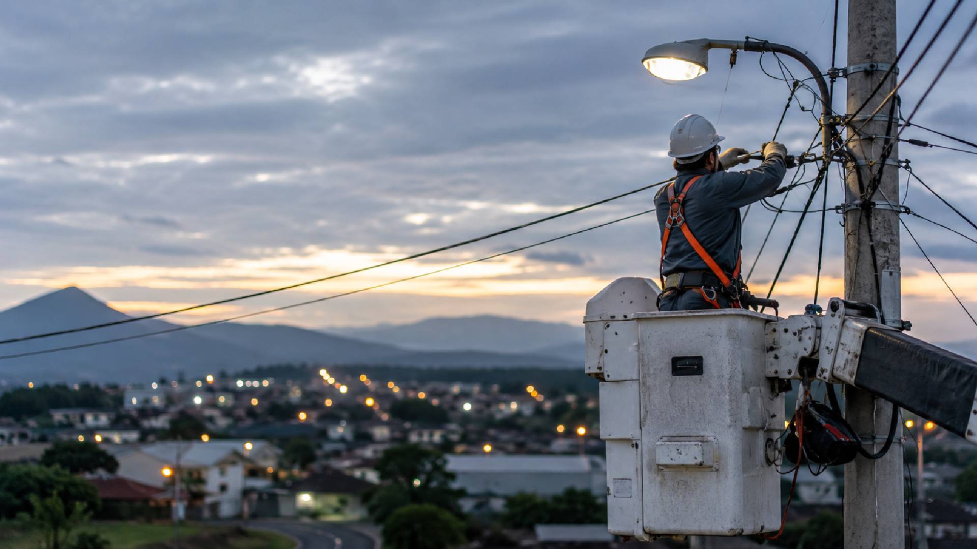 Electric utility technician performing power line maintenance from a bucket truck, supporting reliable electricity distribution and essential energy services