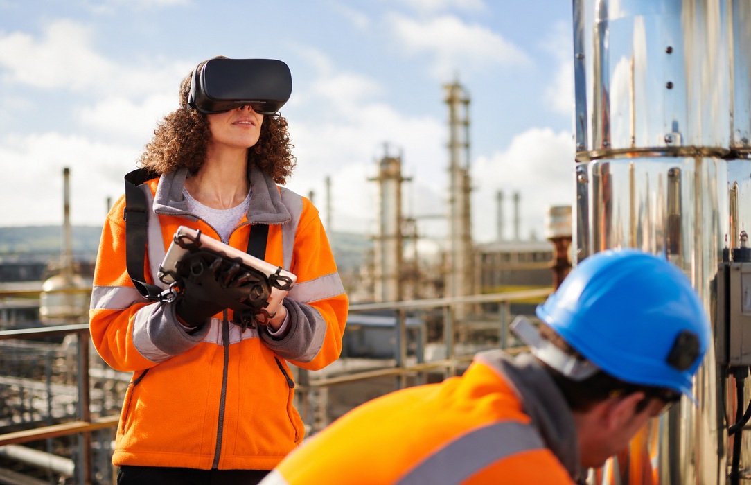 Engineer wearing a virtual reality headset and holding a rugged device in an industrial facility, representing immersive rehearsal before hands-on work.