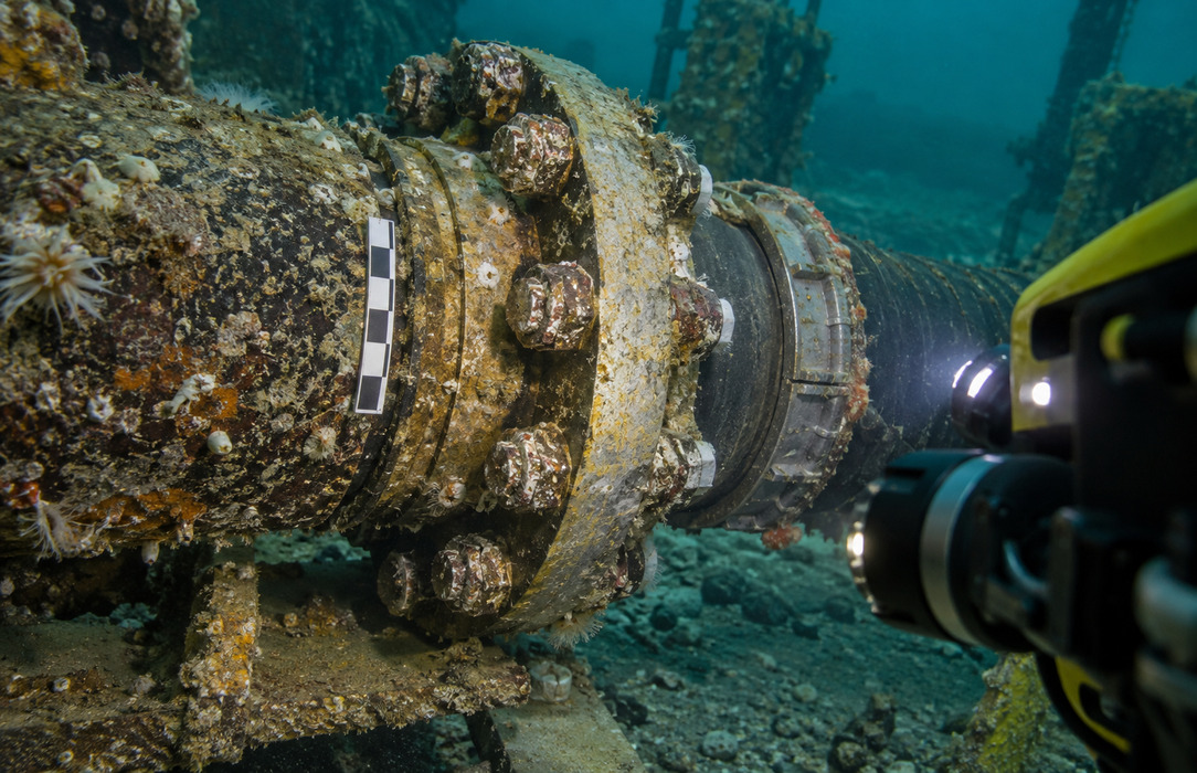 Underwater camera system documenting a marine-grown subsea pipe flange and connection for engineering review.