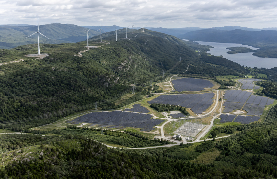 Wind turbines and solar generation assets extend across mountainous terrain, showing a geographically dispersed multi-technology fleet.